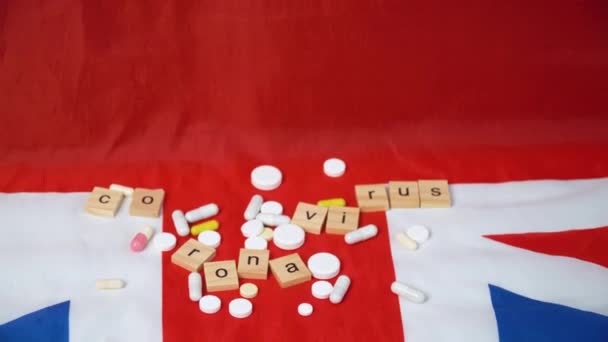 Смешанные таблетки на флаге Великобритании с надписью коронавирус. Коронавирус в Великобритании. Победа над коронавирусом. Вакцина Ковида-19 — стоковое видео