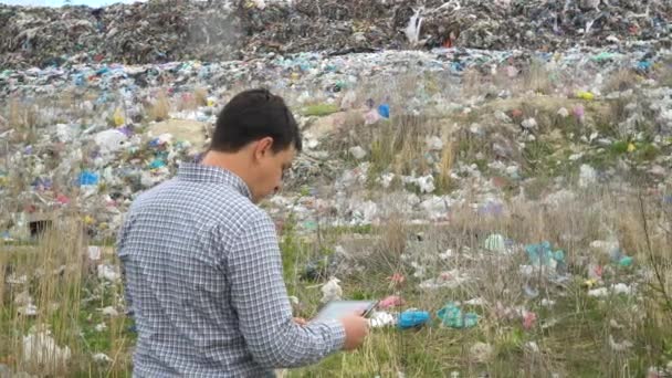 El inspector de basuras registra el nivel de contaminación en el basurero. Concepto de contaminación ecológica — Vídeos de Stock