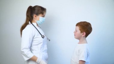Kadın doktor bir çocuğa koruyucu maske takıyor. Covid-19 koruması