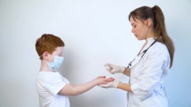 Bir kadın doktor, küçük bir çocuğun ellerini antiseptik spreyle dezenfekte ediyor. Covid-19 koruması. Koronavirüsü durdurun.