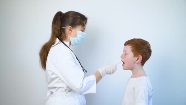 Pediatra a verificar a garganta de um menino. Teste de esfregaço de garganta infantil para detectar covid-19 ou usando aplicador — Vídeo de Stock