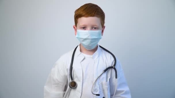 Close-up van Kaukasische littiel arts met een stethoscoop in beschermend masker. Littiele arts trekt zwarte beschermende handschoenen aan — Stockvideo