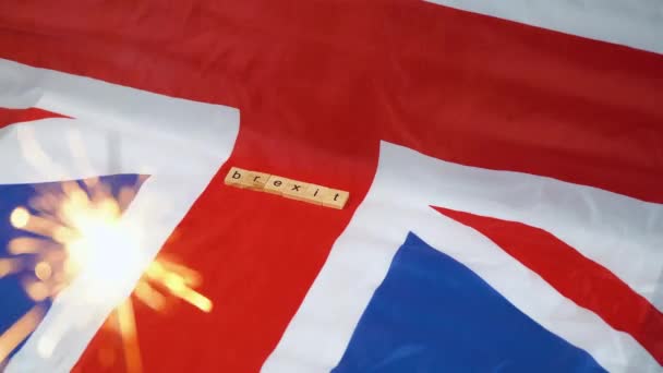 Wunderkerze auf dem Hintergrund der britischen Flagge mit der Aufschrift Brexit und Schere. Brexit in Großbritannien. Großbritannien feiert Austritt aus der Europäischen Union — Stockvideo