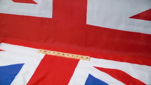 Gemischte Pillen fallen auf britische Flagge mit der Aufschrift Coronavirus. Coronavirus in Großbritannien. Sieg über das Coronavirus. Covid-19-Impfstoff — Stockvideo