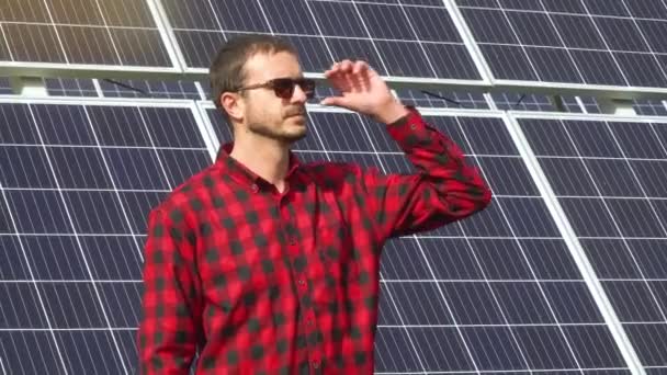 Retrato de um jovem engenheiro bem sucedido no fundo de uma usina solar. Motores instalando novas baterias ensolaradas — Vídeo de Stock