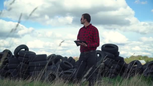 Inspector records pollution level on tire dump. Ecology pollution concept. Recycled tire pile. Old car rubber, tire — Stock Video