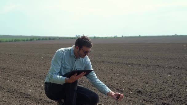 El agricultor toma una muestra de suelo. Agricultor con una tableta comprueba el suelo antes de sembrar cultivos — Vídeo de stock