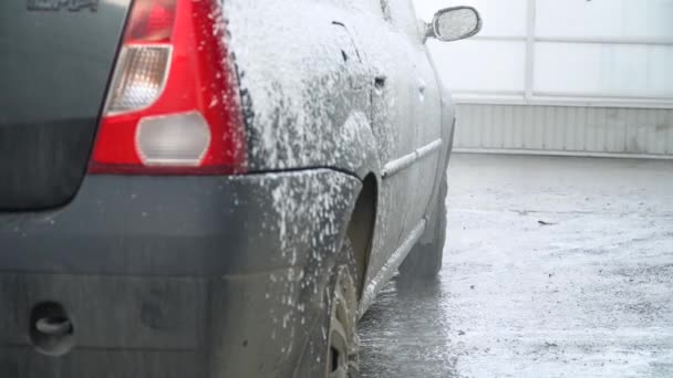 Un hombre en el lavado de coches está lavando un coche en las suds por mangueras de agua. Auto-servicio de lavado de coches — Vídeo de stock