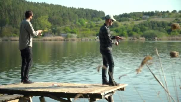 Двое мужчин рыбачат на озере. Крутящаяся хищная рыба — стоковое видео