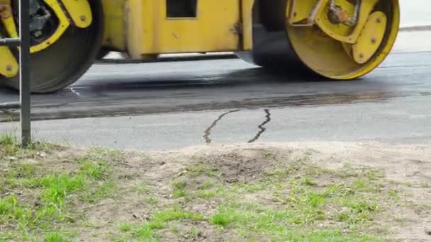 El rodillo amarillo de la carretera monta en una carretera mientras que pone asfalto. Construcción de una nueva carretera — Vídeo de stock