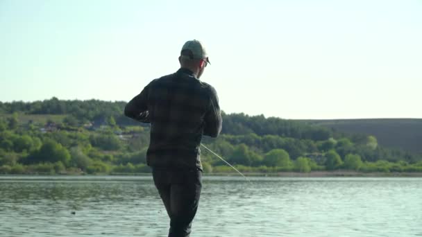 Pescador moldado haste de pesca no lago ou água do rio. Spinning pesca peixes predadores — Vídeo de Stock