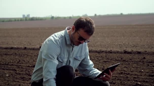 Boer met een tablet controleert de grond voor het zaaien van gewassen. Boer neemt een bodemmonster — Stockvideo