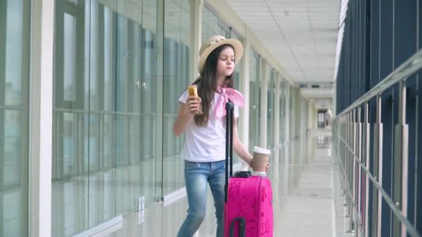 La niña come comida rápida y bebe café en el aeropuerto mientras espera el avión. Retardo de vuelo — Vídeo de stock