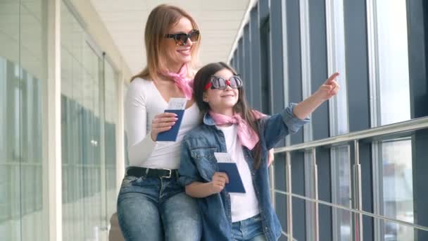 Mamma e figlia in possesso di passaporti e biglietti aerei per l'imbarco. Carta d'imbarco e passaporto in aeroporto. Ragazza mostra puntando con il dito — Video Stock