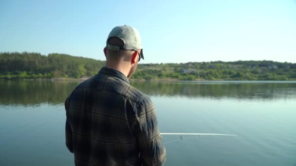 Молодой человек рыбачит на озере. Крутящаяся хищная рыба — стоковое видео