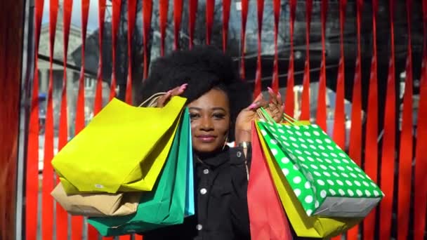 Boldog afrikai lány, piros hátterű bevásárlószatyrokkal. Vásárlási koncepció — Stock videók