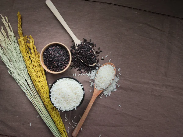 Riso tailandese crudo, riso bianco e marrone su ciotola e cucchiaio di legno — Foto Stock