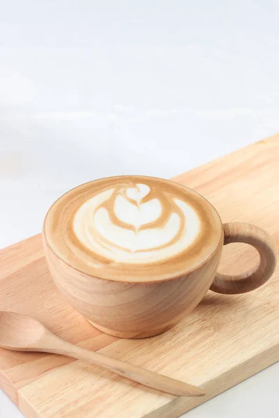 Café arte tardia em xícara de madeira na bandeja branca bakcground, com colher — Fotografia de Stock