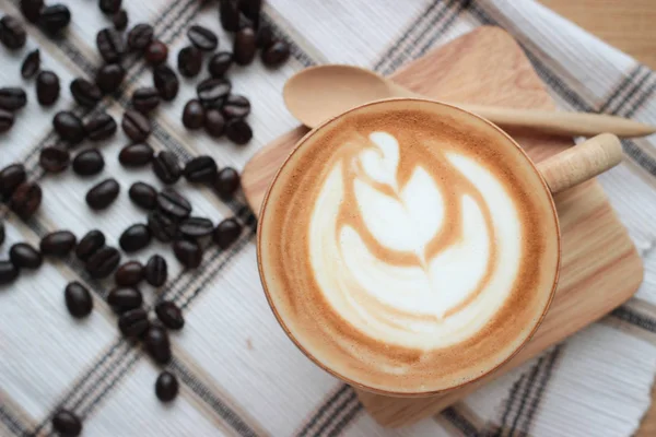 Kaffee-Spätkunst in Holztasse auf Tablett und Kleidungsstück, mit Löffel und B — Stockfoto