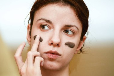 Yüzünün derisini yüzmek için koyu kömür maskesi kullanan bir model.
