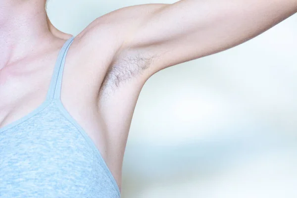 A woman displaying a hairy armpit before shaving it