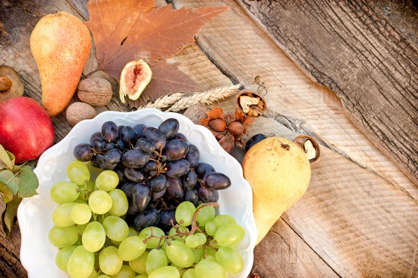 Seasonal organic fruits on plate and on rustic table — Stock Photo, Image