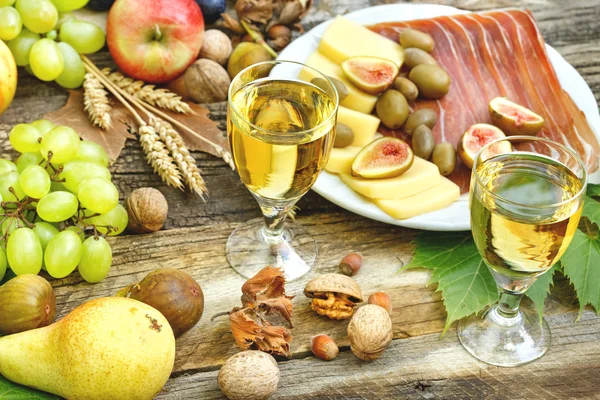 Weißwein, Prosciutto, Käse und saisonale Früchte auf rustikalem Tisch — Stockfoto