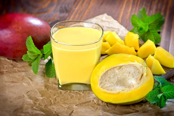Mango smoothie (mango juice) och färsk mango på bord — Stockfoto