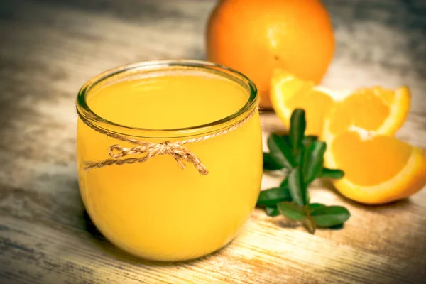 Apelsinjuice på rustika bord - färskpressad apelsinjuice — Stockfoto