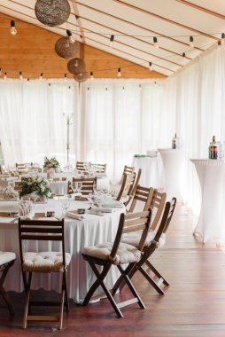 Düğün salonunu köy tarzında dekore etmek. Tahta sandalyeler, beyaz bir masa örtüsü, minimalizm, çelenkler, terastaki zemin pencereleri..