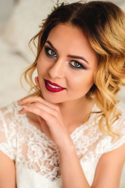 Beyaz saçlı ve parlak makyajlı gelin. Düğün saç stili ve makyaj. Günaydın ve gelinin toplantıları. Kırmızı ruj ve dumanlı gözler.