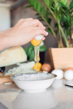 Yumurta kıran ve yumurta yapan bir kadın. İç mekan mutfağı. Kahvaltı hazırlığı..