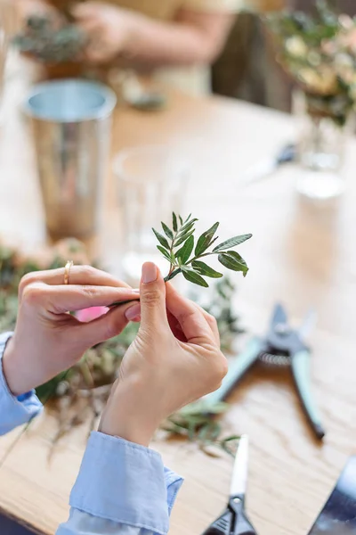 Workshop florist, making bouquets and flower arrangements. Girl makes wreath at head. Process of weaving a wreath with herbs and flowers. Lesson of florists close-up. Copy space