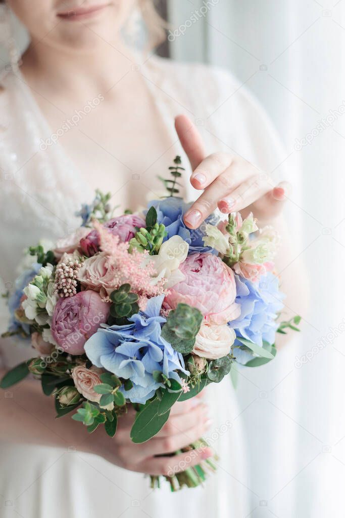 Bridal bouquet Beautiful of pink wedding flowers in hands of the bride. Close-up interior studio shot against window