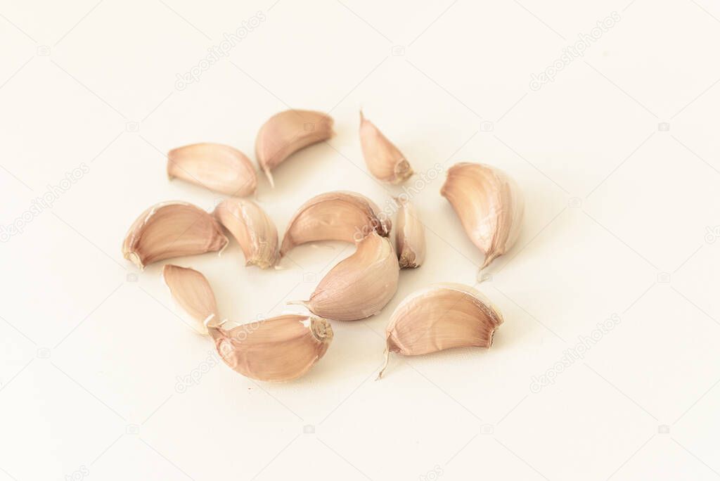 Cloves of garlic on a white plate and table. Healthy food. Prevention and treatment of the disease.