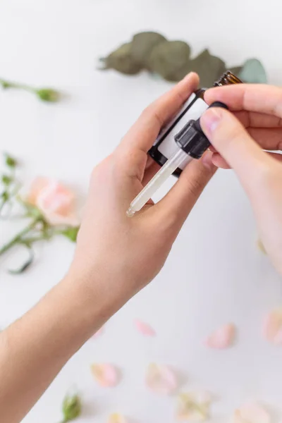 Serum Hand Aanbrengen Het Gezicht Verzorgen Heldere Achtergrond Met Rozenbloemen — Stockfoto