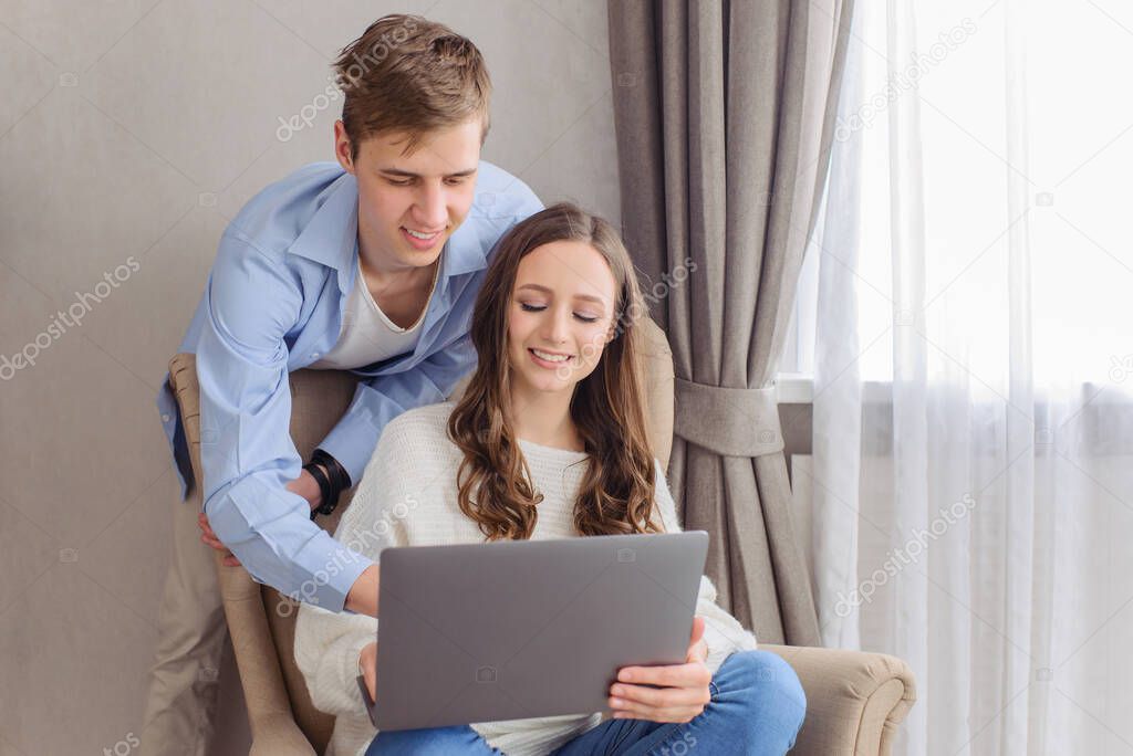 Cheerful couple looking at laptop computer, together on day and weekend off at home. Choose film, building family financial plan, meal planning for healthy style, wedding ideas, ordering gifts, online courses to get apartment on the Internet.