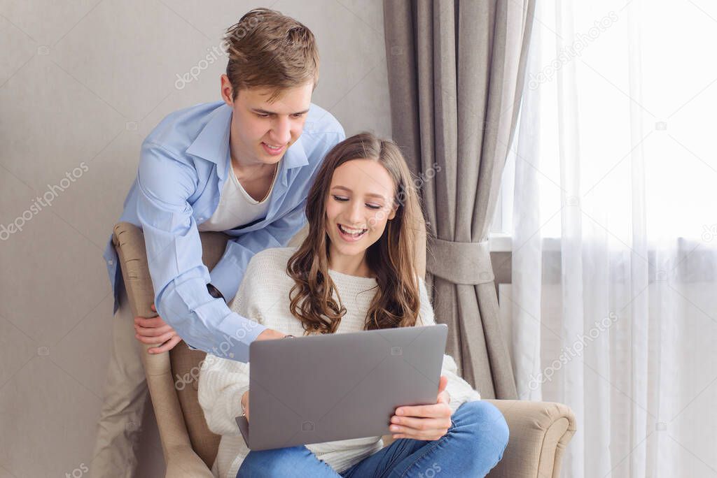 Cheerful couple looking at laptop computer, together on day and weekend off at home. Choose film, building family financial plan, meal planning for healthy style, wedding ideas, ordering gifts, online courses to get apartment on the Internet.