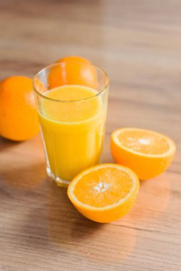 Evin ahşap masasında portakallar soyulmuş, kesilmiş ve taze meyve suyu. Faydalı yiyecekler, sağlıklı vitaminler.