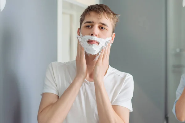 Young Guy Blonde Hair White Jersey Applies Shaving Foam His — Stock Photo, Image