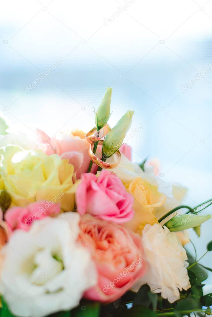 Macro: two gold wedding rings for the groom and bride on a bouquet of roses.