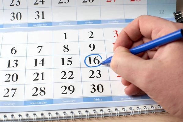 hand marks date on  calendar in blue