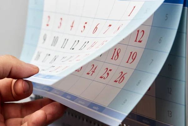 Voltear a mano a través de un calendario de pared — Foto de Stock