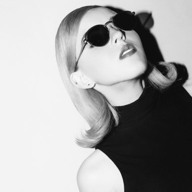 Retro ruh hali. Zarif saç ve şık güneş gözlüğü ile model.