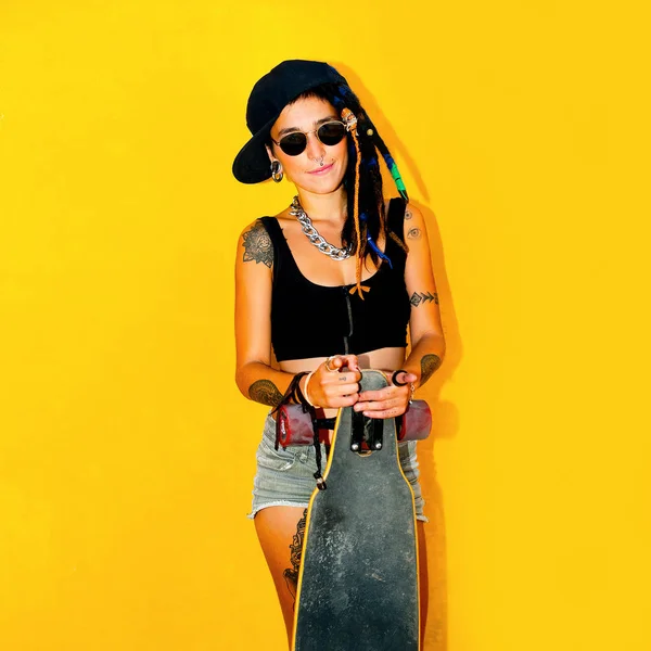 Ragazza adolescente di moda con dreadlocks e tatuaggi. Skateboard s — Foto Stock