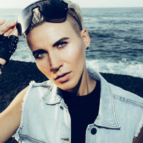 Şık sarışın portre. Mavi jeans ve trendy güneş gözlüğü.