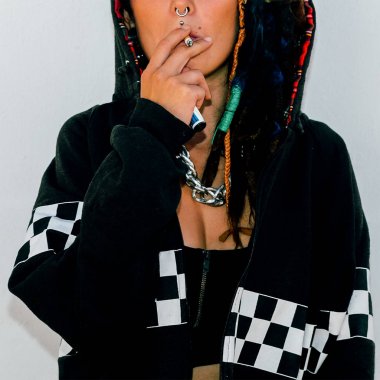 Kız sokak stil. Duvar arka plan üzerinde bir sigara ile. Kentsel