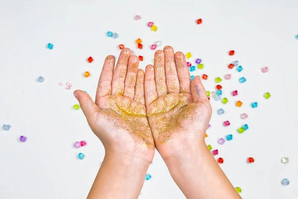 Barnens händer, händer som håller pärlor på en vit bakgrund — Stockfoto
