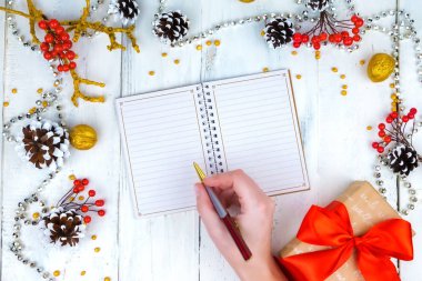 Noel ahşap arka plan koniler ve Not Defteri ile. Not defterinde yazmak eller.