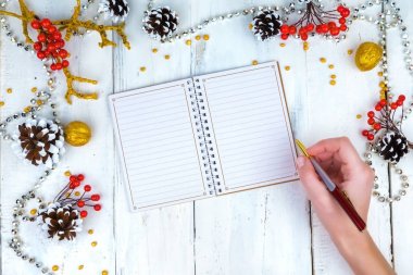 Noel ahşap arka plan koniler ve Not Defteri ile. Not defterinde yazmak eller.